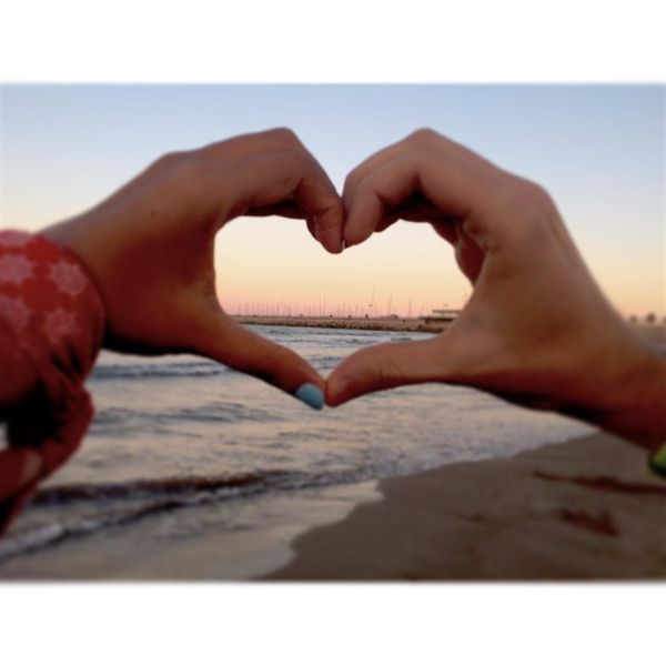 a symbol of love from the hands on the background of the sea